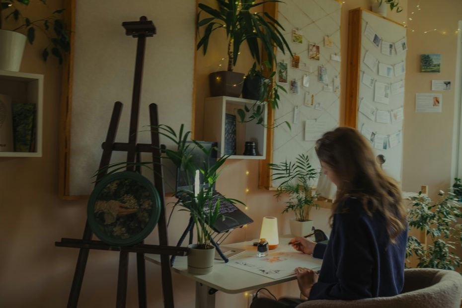 Empreendedora criativa a pintar numa secretária com computador portátil e plantas em volta